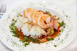 Shrimp over white rice with sauce and vegetables