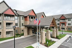 Modern apartment complex with covered entrance and flags