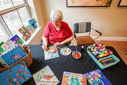 Senior woman painting at table with art supplies