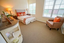 Bright bedroom with orange accents and armchair