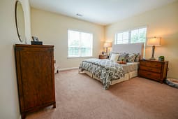Bright bedroom with gray bedding and wooden furniture