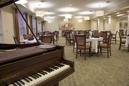 Elegant dining room with grand piano and round tables