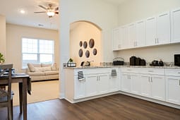 Modern white kitchen with granite countertops and archway