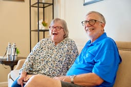Smiling elderly couple sitting on living room couch