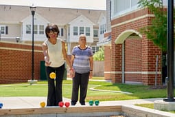 Two elderly women playing bocce outdoors