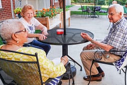 Three seniors chatting at outdoor patio table