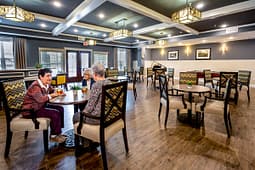 Three seniors chatting at table in community lounge