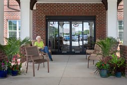 Elderly woman sitting outside brick building entrance