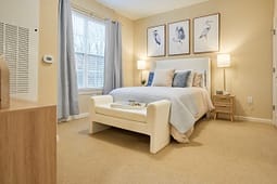 Cozy beige bedroom with bed and bird artwork