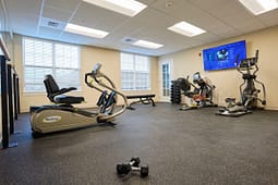 Small fitness room with cardio machines and weights