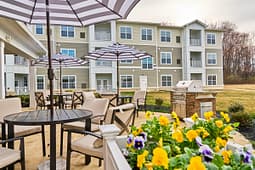 Apartment complex patio with tables, umbrellas, and grill