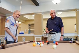 Two senior men playing pool indoors