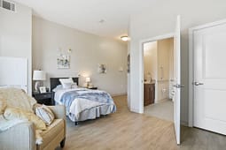 Modern bedroom with accessible ensuite bathroom and armchair