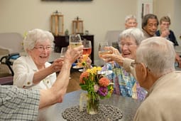 Seniors toasting with wine at table with flowers