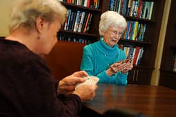 Two elderly women playing cards at table