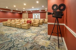 Private theater room with beige chairs and vintage camera