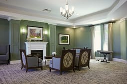 Elegant green living room with fireplace and chairs