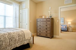 Cozy bedroom with wooden dresser and adjacent sitting area