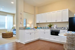 Bright kitchenette with white cabinets and granite countertops