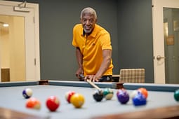 Man aiming cue stick at pool table