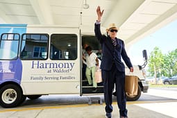 Senior man waving while exiting community shuttle bus