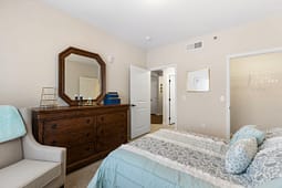 Neutral bedroom with wooden dresser and blue bedding