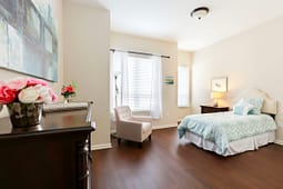 Bright staged bedroom with teal bedding and armchair
