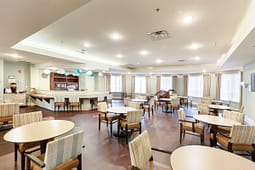 Bright community dining room with round tables and piano