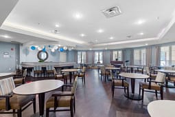 Spacious community dining room with round tables and piano