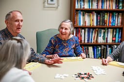 Seniors playing dominoes at a table indoors