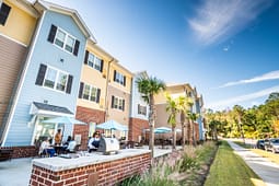 Modern apartment building with outdoor patio and palm trees