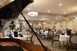 Elegant dining room with grand piano and set tables