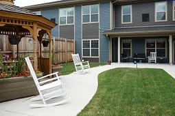 Landscaped backyard with gazebo and white rocking chairs