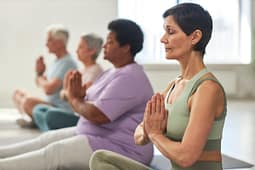 Group practicing seated yoga with hands in prayer