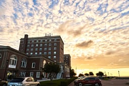 Brick waterfront building at sunset with parked cars