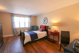 Cozy single bedroom with wooden floors and lamp