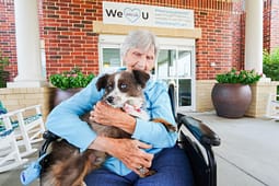 Elderly woman cuddling dog outside care facility