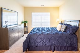 Modern bedroom with blue bedding and dresser mirror
