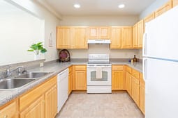 Bright kitchen with light wood cabinets and white appliances