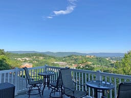 Balcony seating overlooking green mountains and blue sky