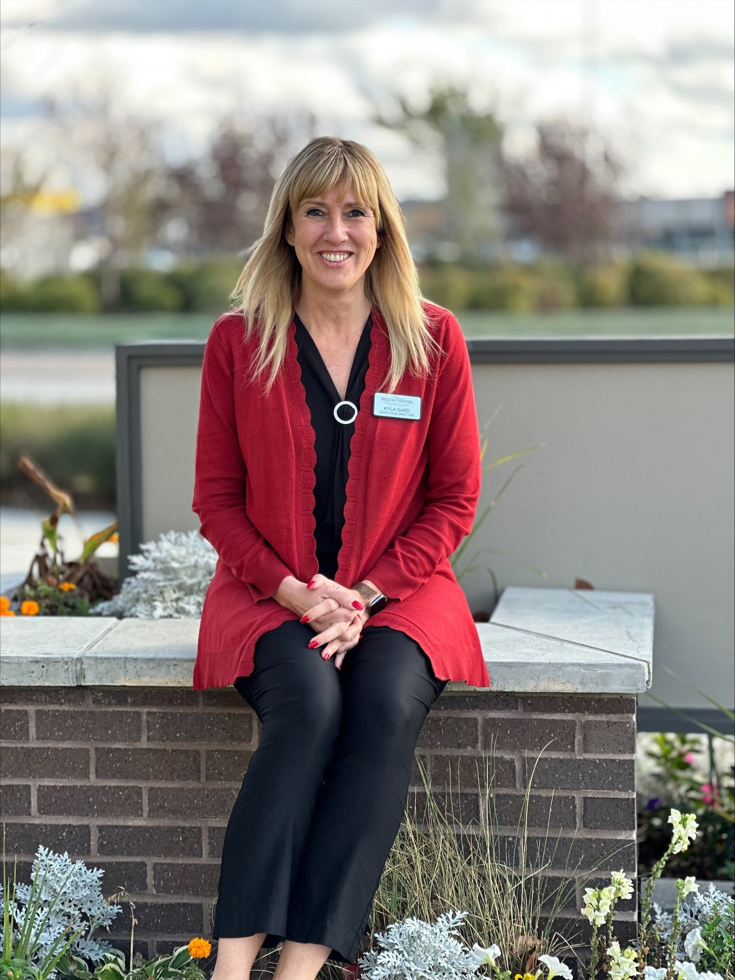 Smiling woman in red cardigan sitting outdoors