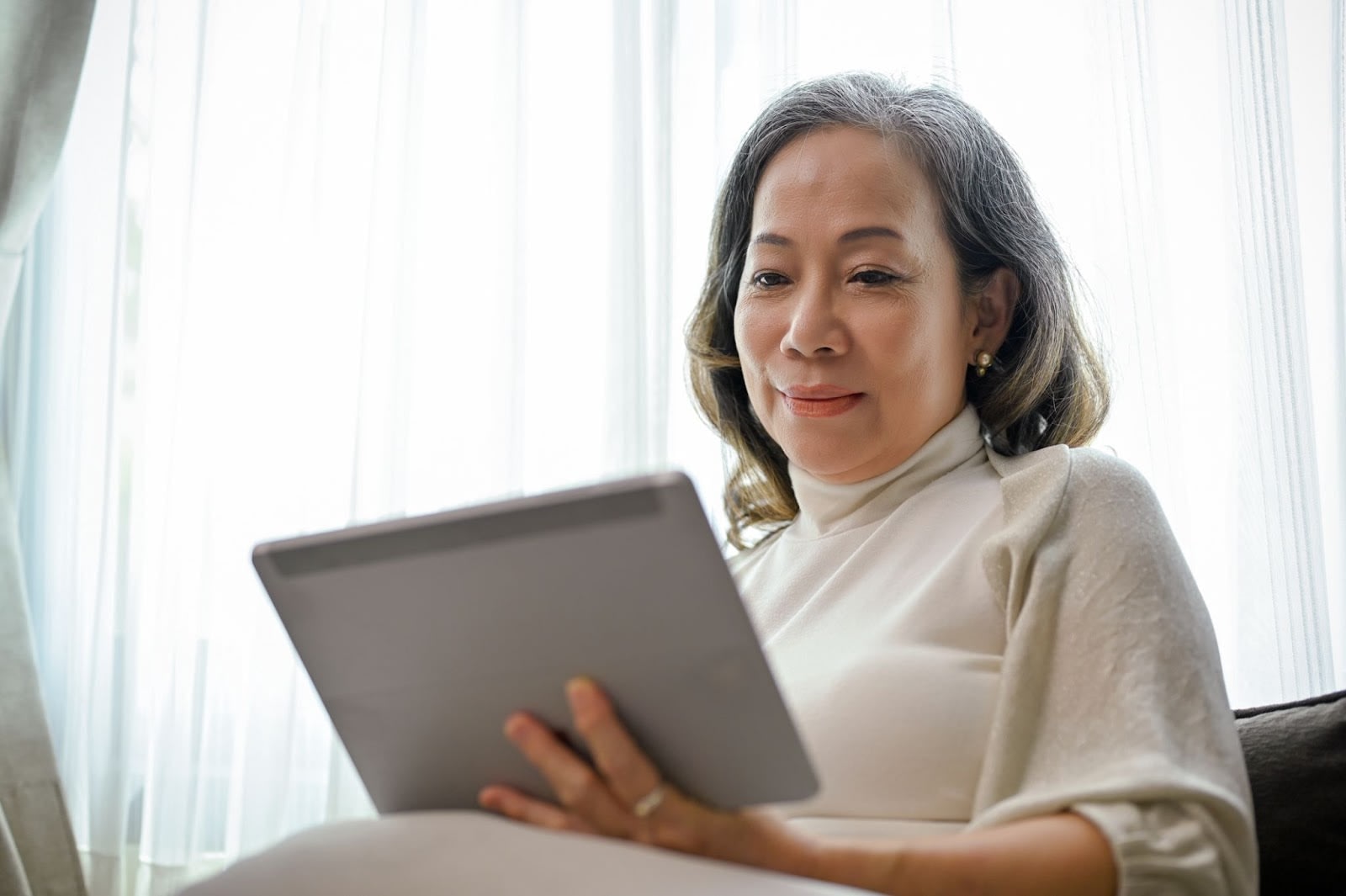 An older woman smiling while holding a tablet