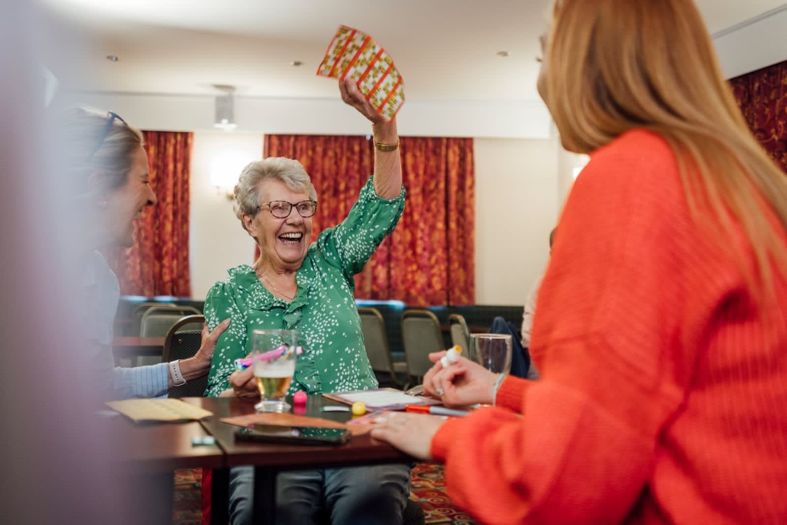 Senior woman smiling and holding up a winning bingo card