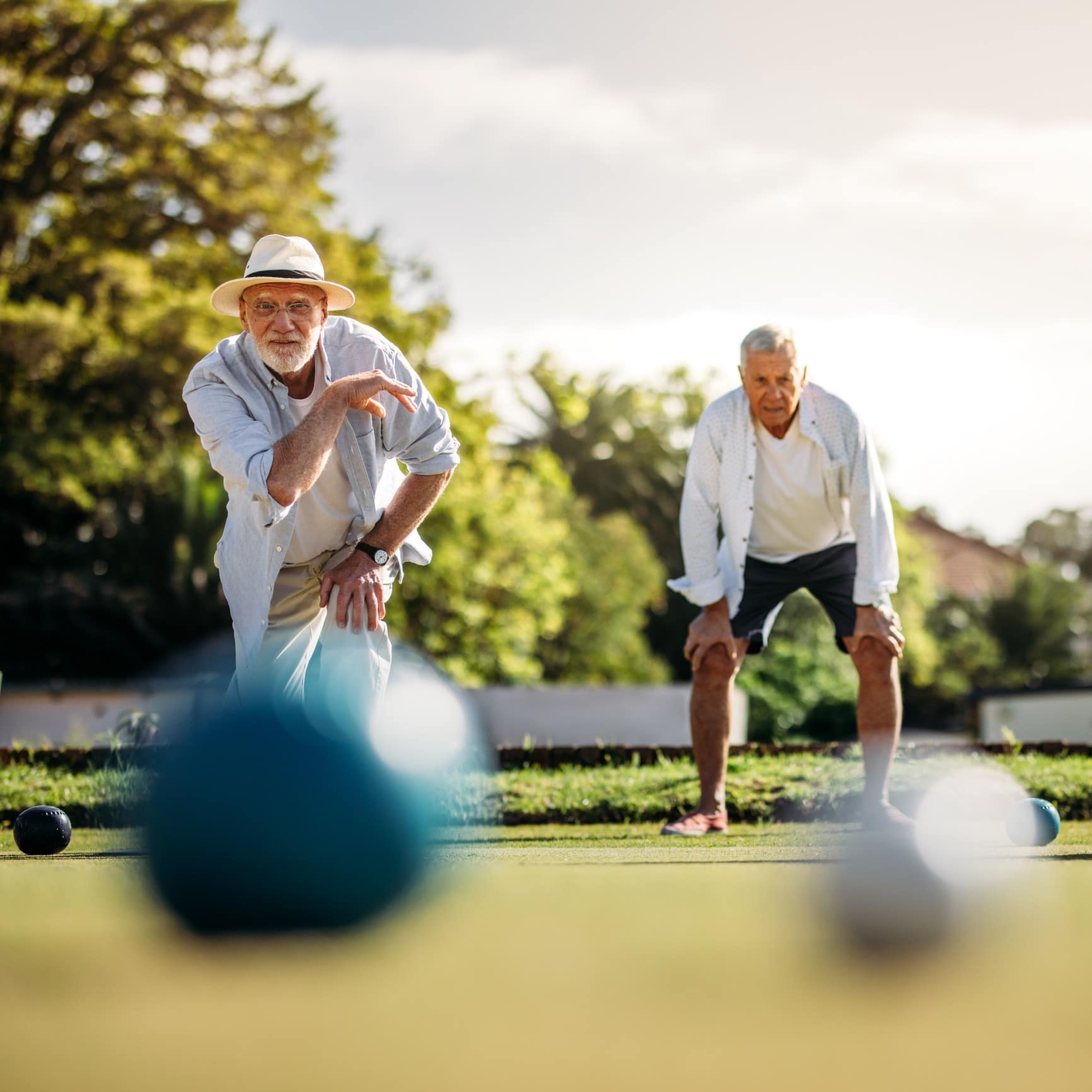 Two elderly men playing lawn bowls outdoors