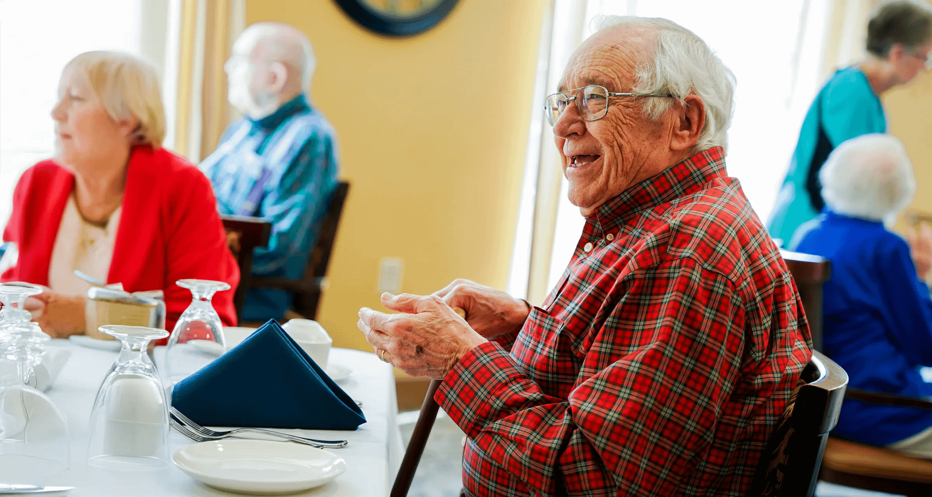 Elderly man smiling at dining table with others
