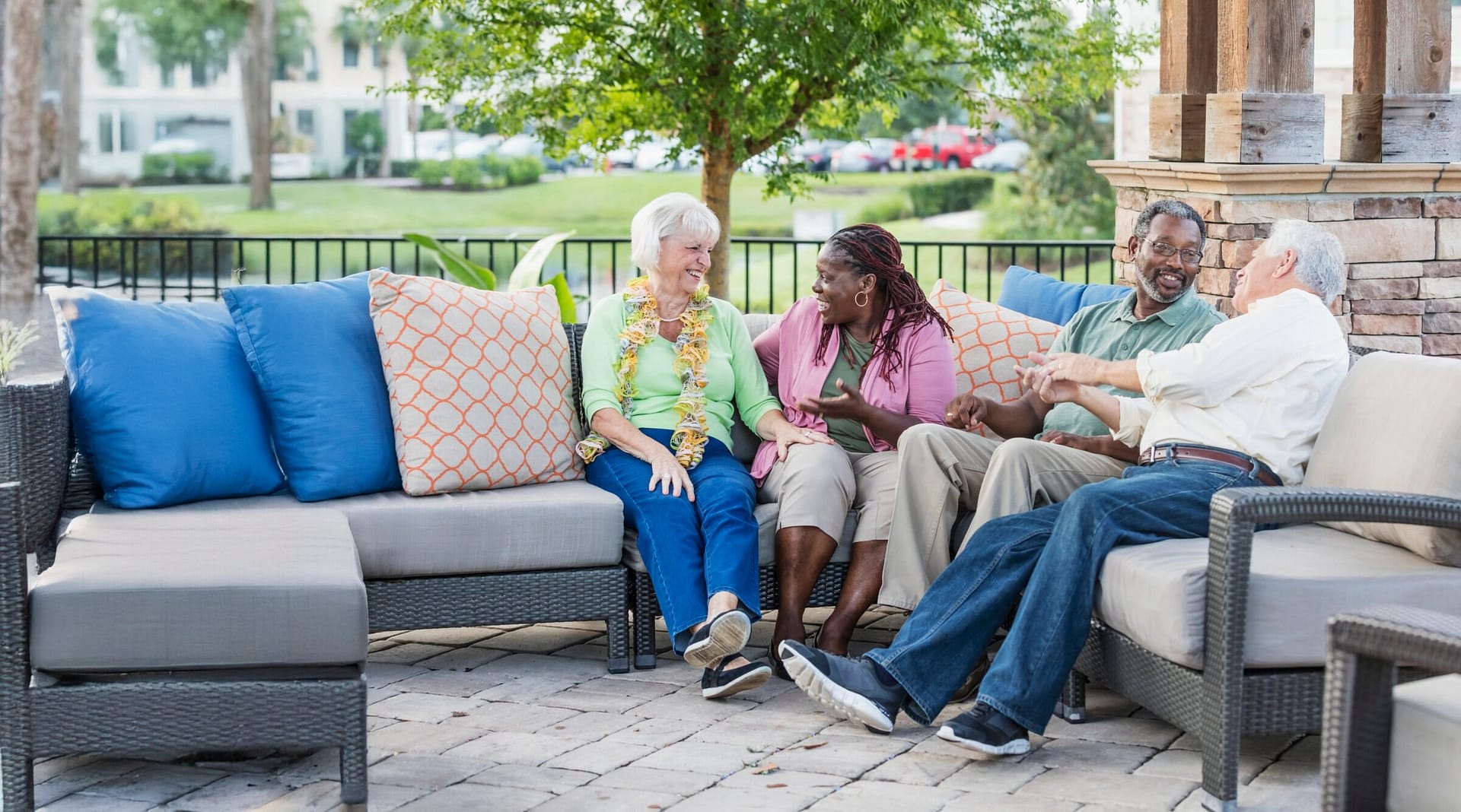 Four seniors chatting on outdoor patio sofa