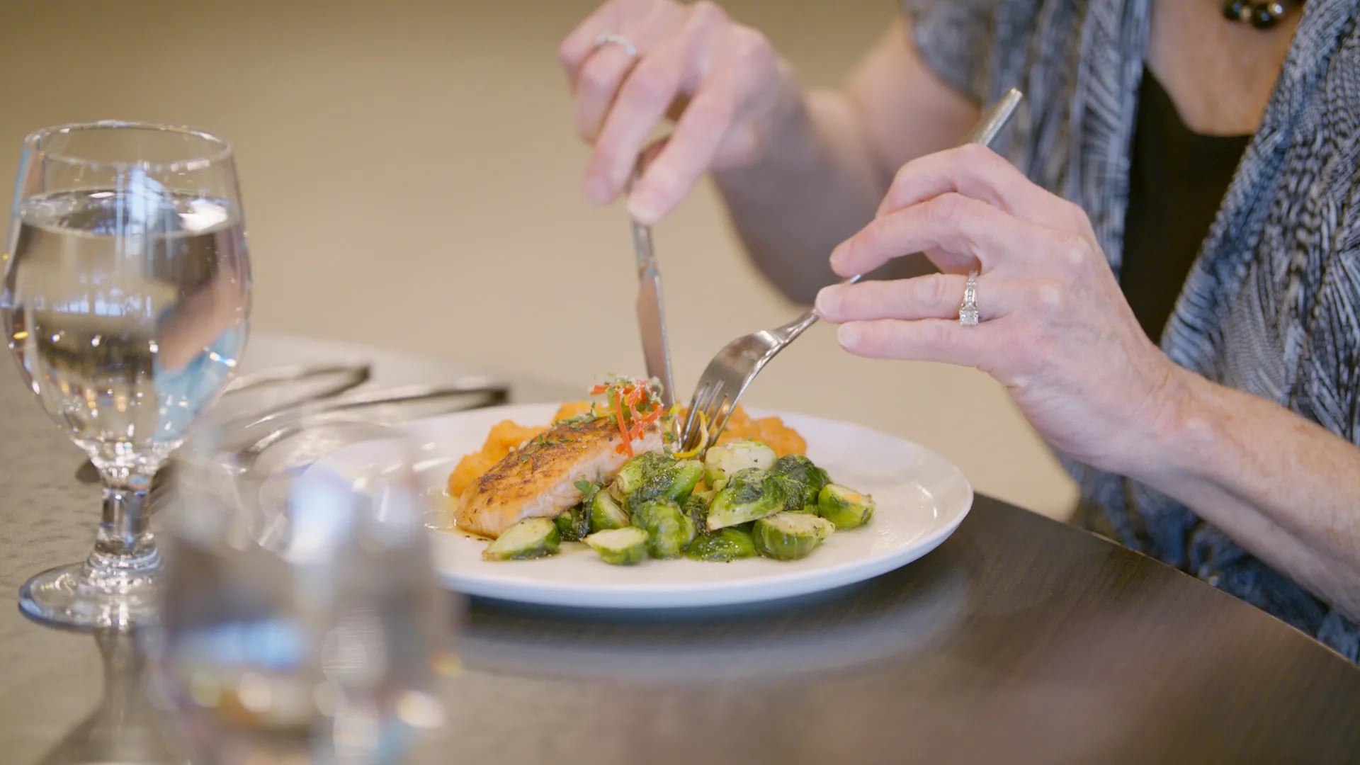 Person eating salmon with Brussels sprouts and water