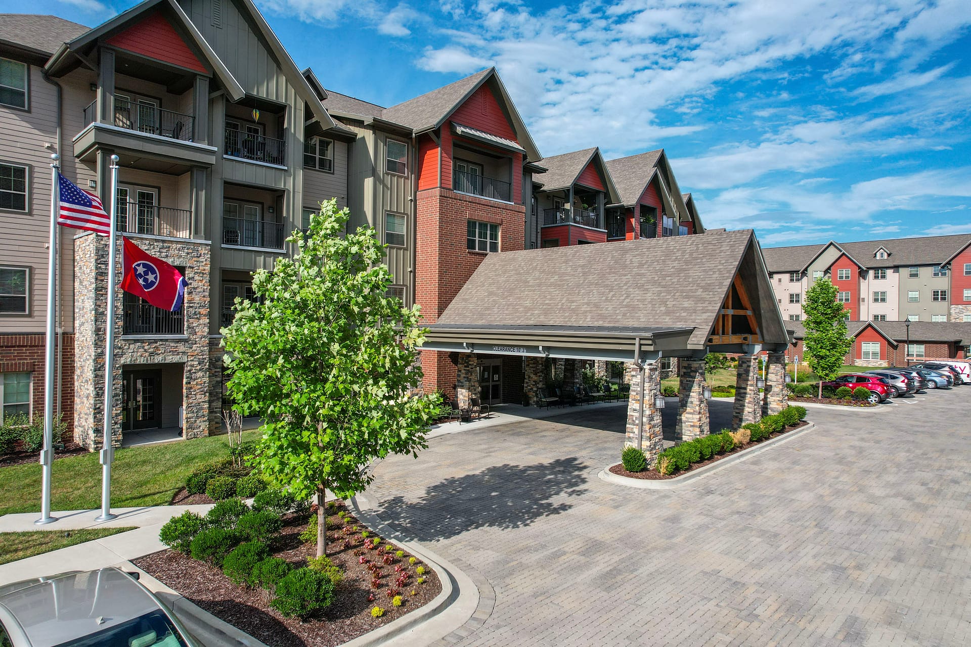 Modern apartment complex with covered entrance and flags