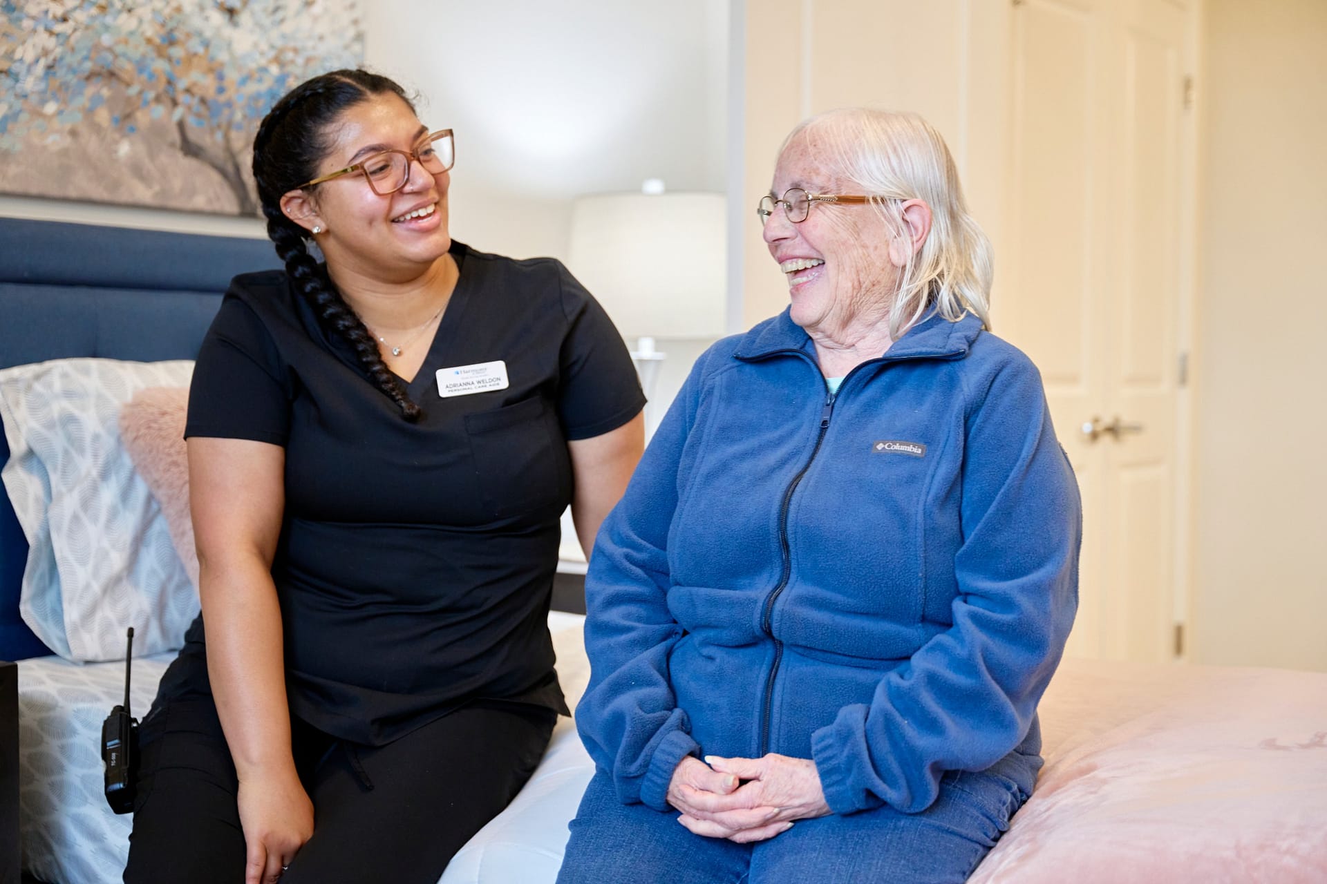 Caregiver and elderly woman smiling on a bed