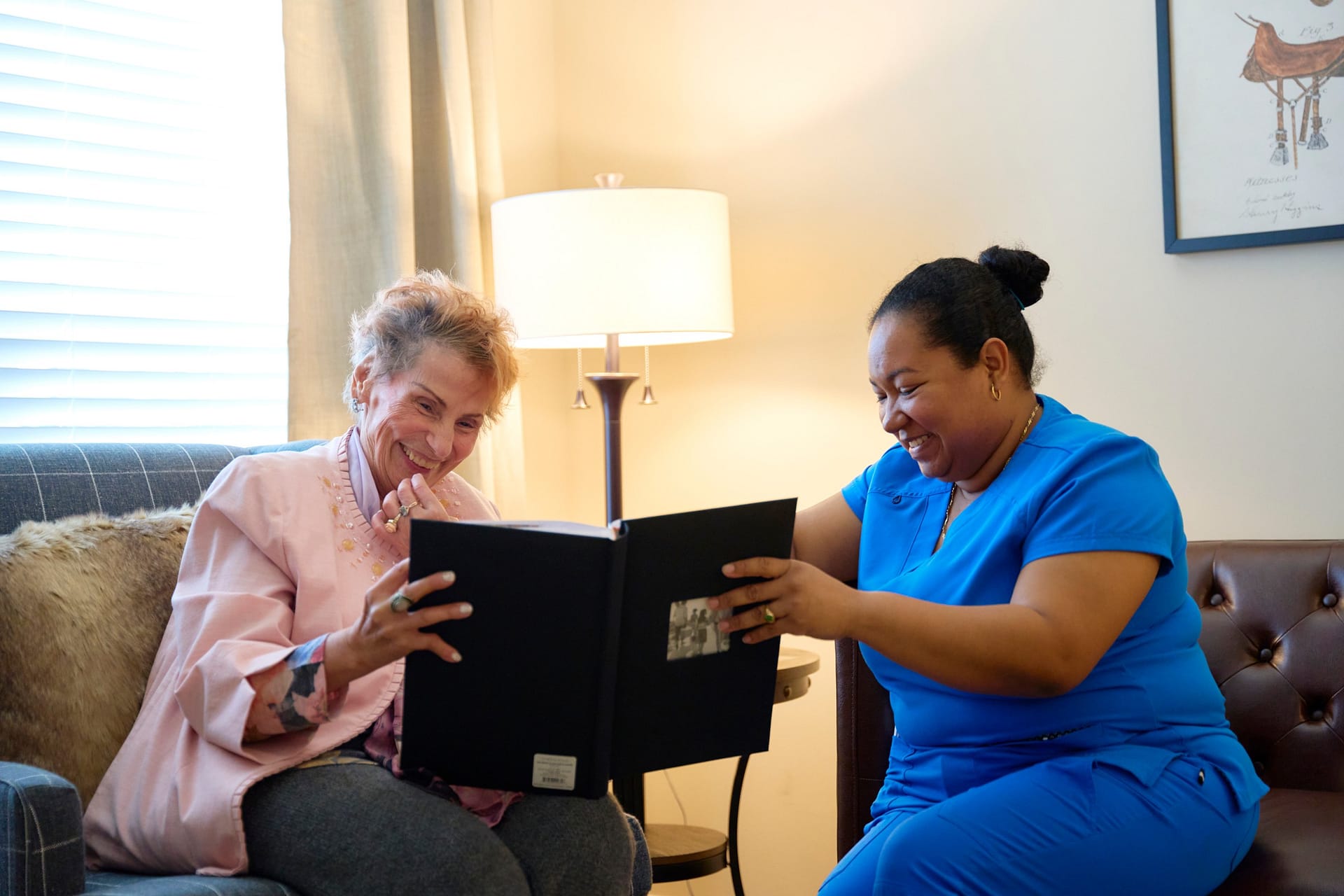 Two women smiling while looking at photo album